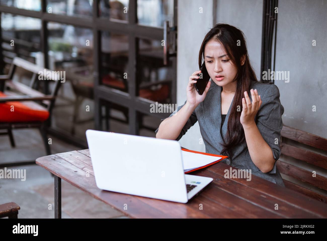 confused young businesswoman while using her mobile phone during working Stock Photo