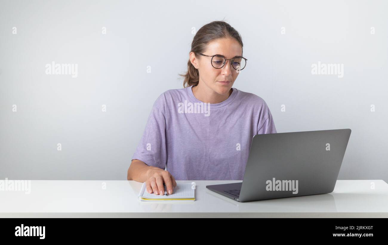 A female student sits at a laptop with a notebook and a pen. High quality photo Stock Photo