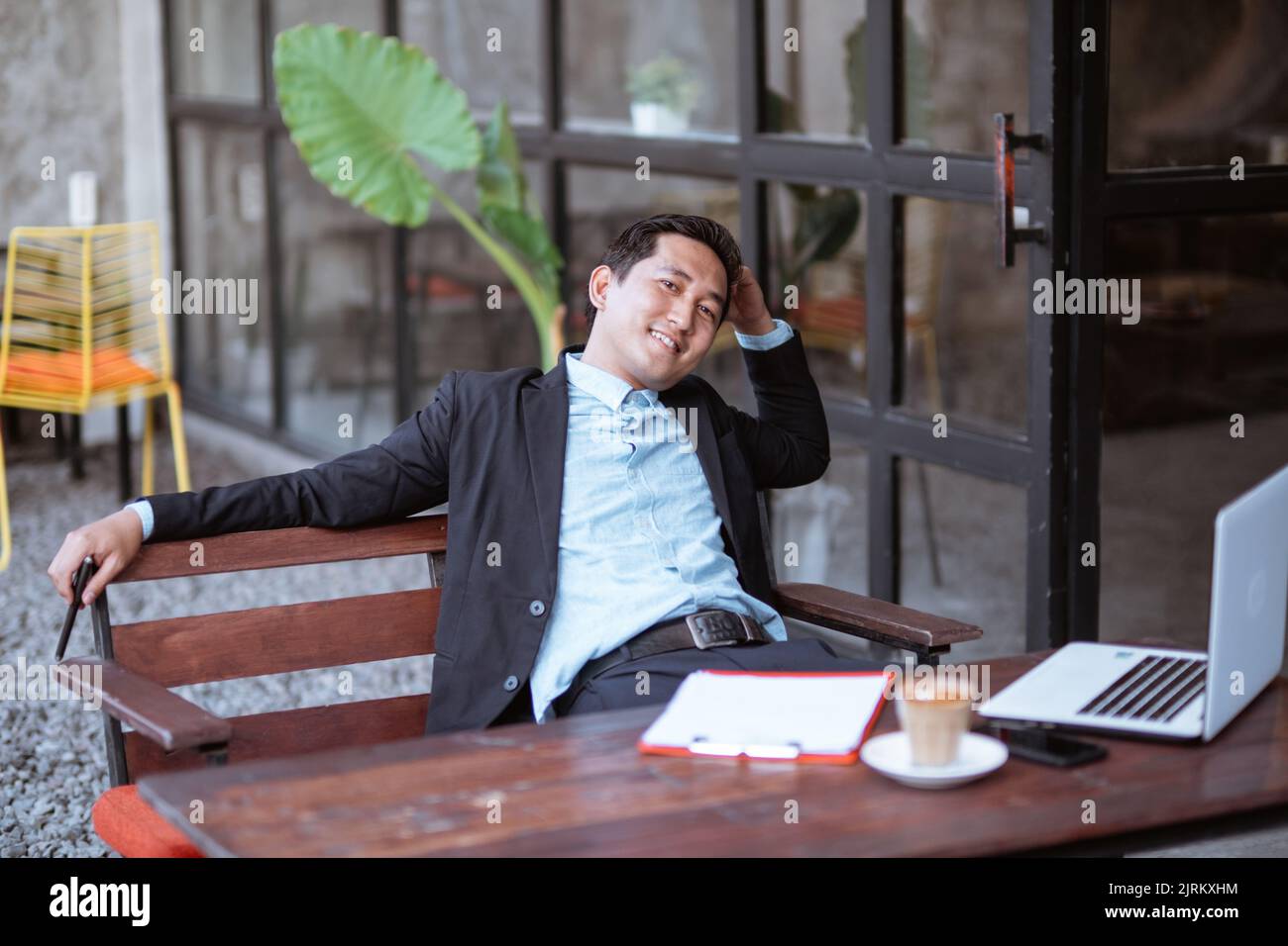 relaxed young businessman sitting in cafe using laptop Stock Photo