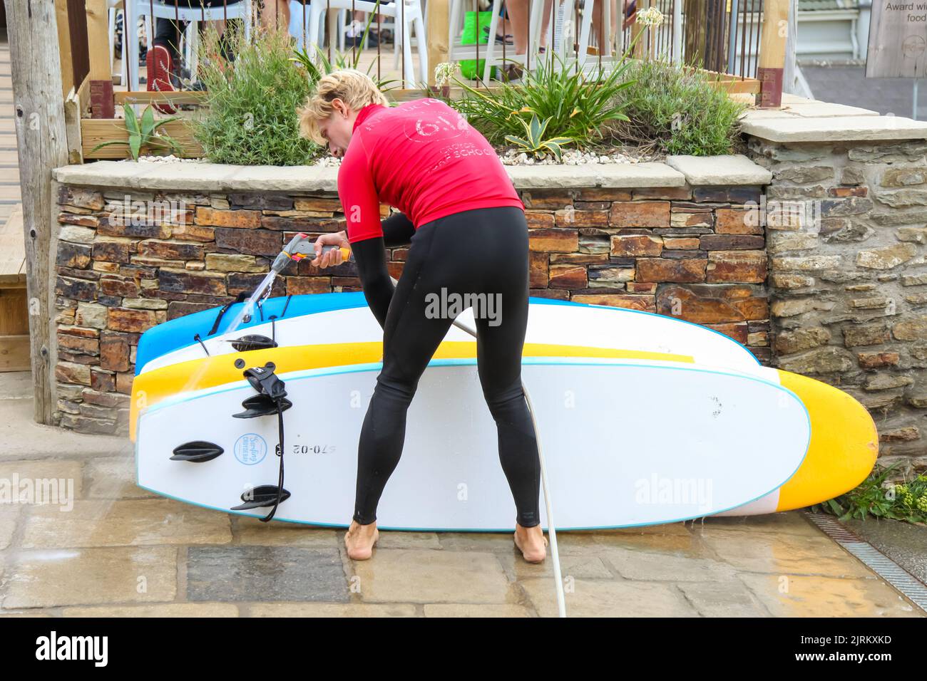 Man washing surf board, Croyde Surf School, Braunton, Devon, England, UK, August 2022 Stock Photo
