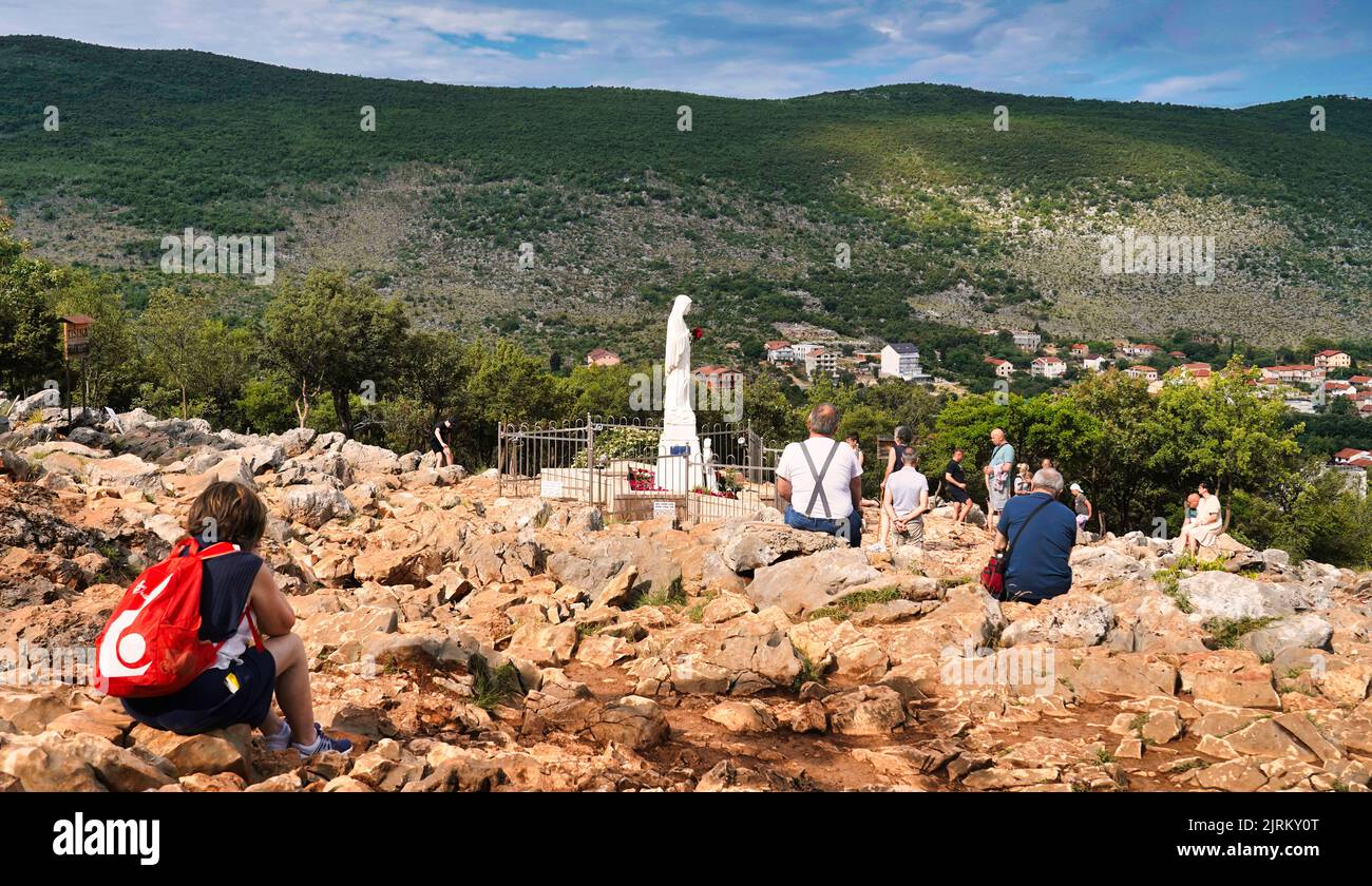 The statue of the Blessed Virgin Mary on Podbrdo (apparition hill) and some of the faithful gathered in prayer (Medjugorje, Bosnia and Herzegovina) Stock Photo