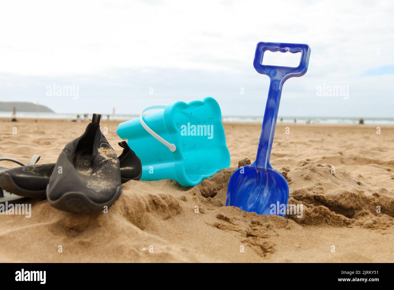 Bucket and Spade with beach shoes in sand at beach, North