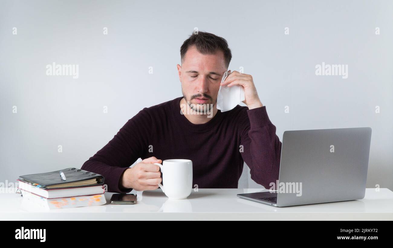 Sick in the workplace - a man with a runny nose and headache in the office. High quality photo Stock Photo