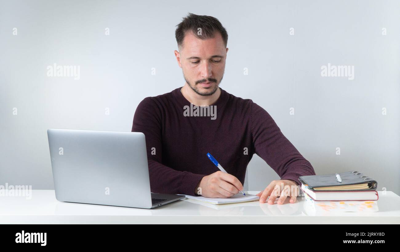 A man writes in a notebook at his desk in the office or at home. High quality photo Stock Photo