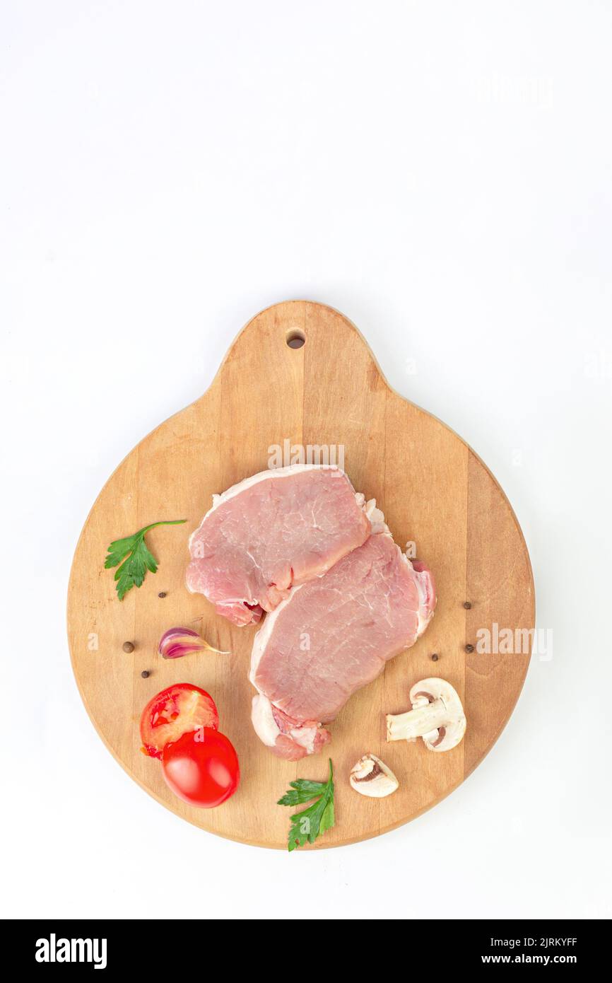 Fresh raw meat with herbs, garlic, tomato, spice, pepper, champignon on rustic background. Stock Photo