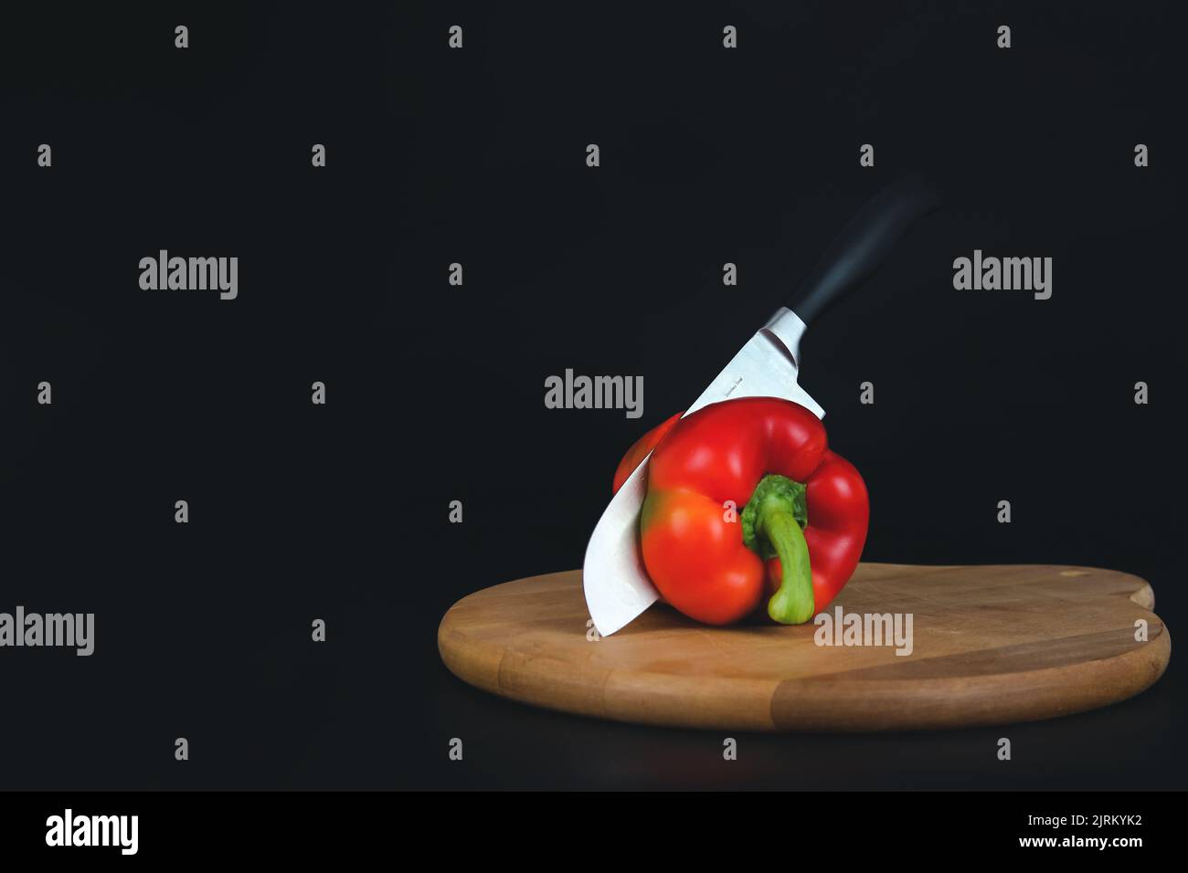Cutting Sweet red pepper with a kitchen knife on the board. Stock Photo