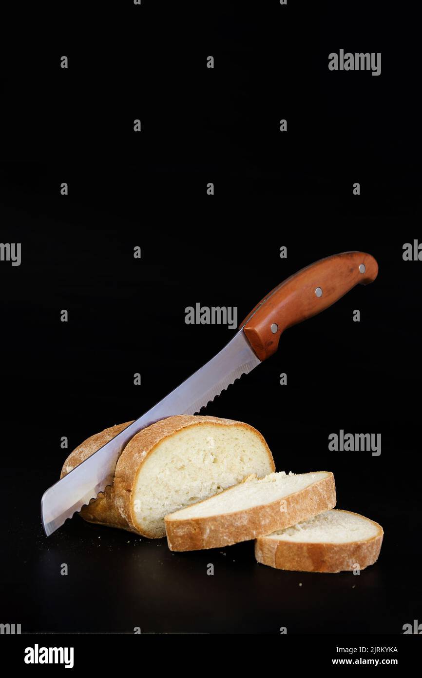 Cutting loaf of bread with knife on cutting board. Stock Photo