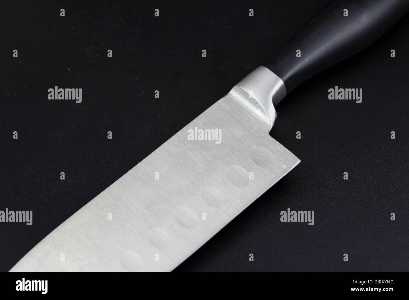 Knife edge, Big kitchen knife with black plastic handle on black background Stock Photo