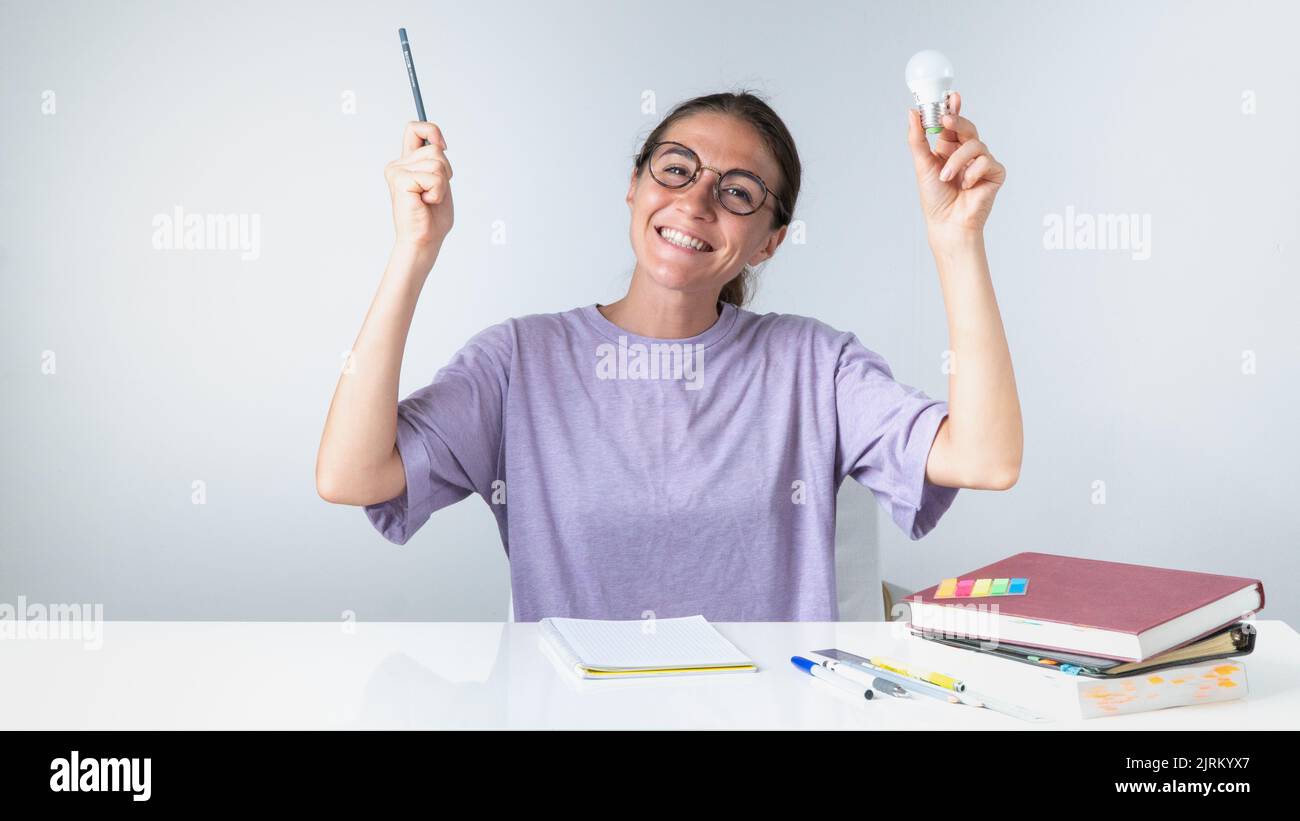 A joyful student with a pencil and a light bulb, an idea or answer came during her studies. High quality photo Stock Photo
