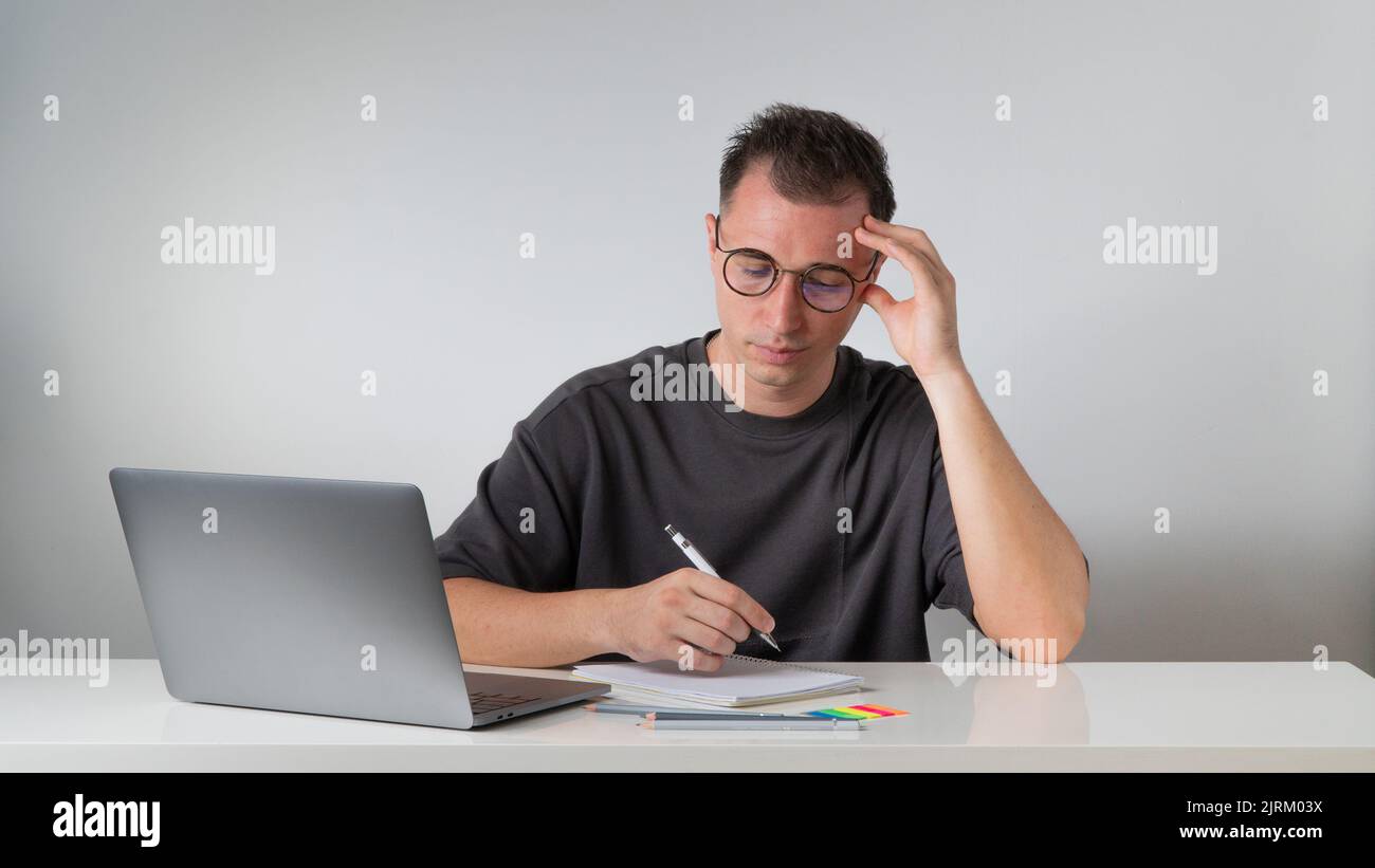 A focused male student writes in a notebook - work and study Stock Photo