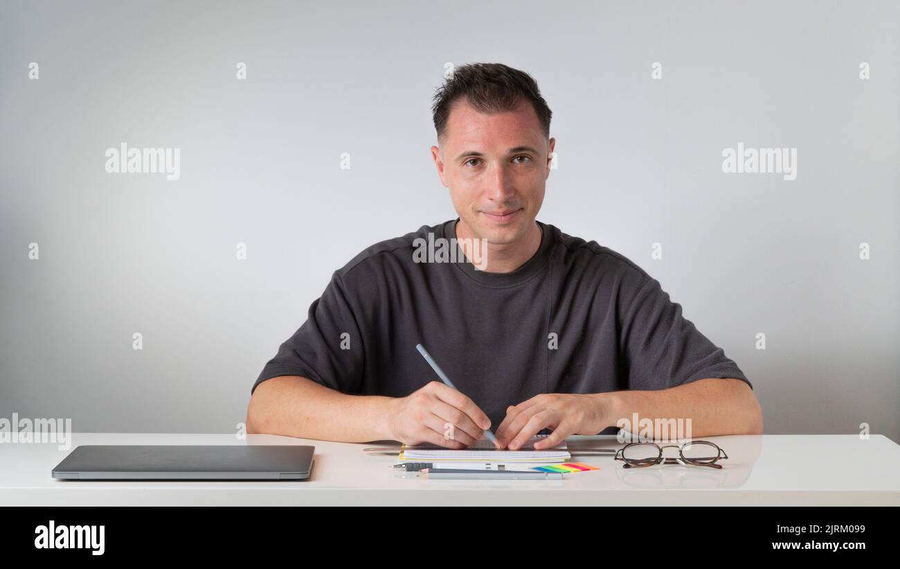 The guy at the desk makes notes in a notebook - study and work Stock Photo