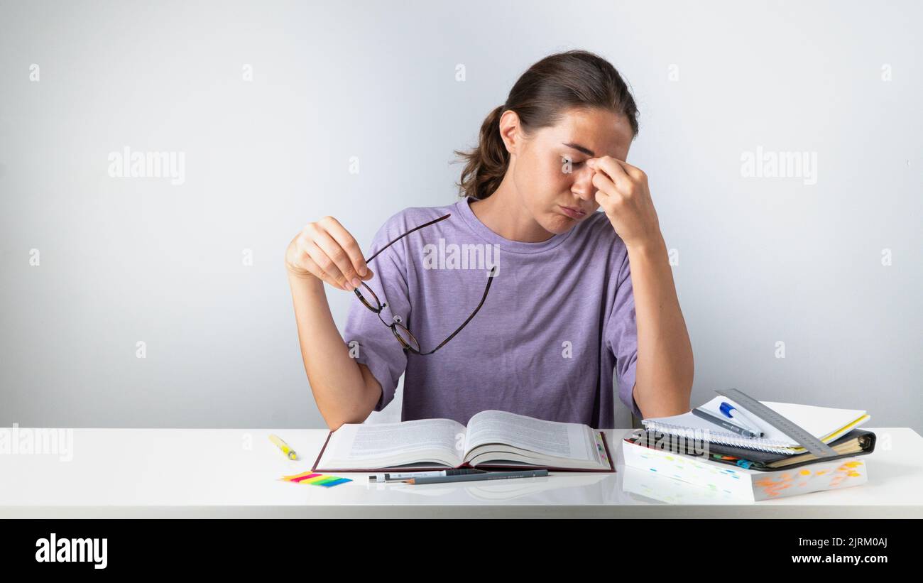A tired student takes off his glasses and rubs his eyes. High quality photo Stock Photo