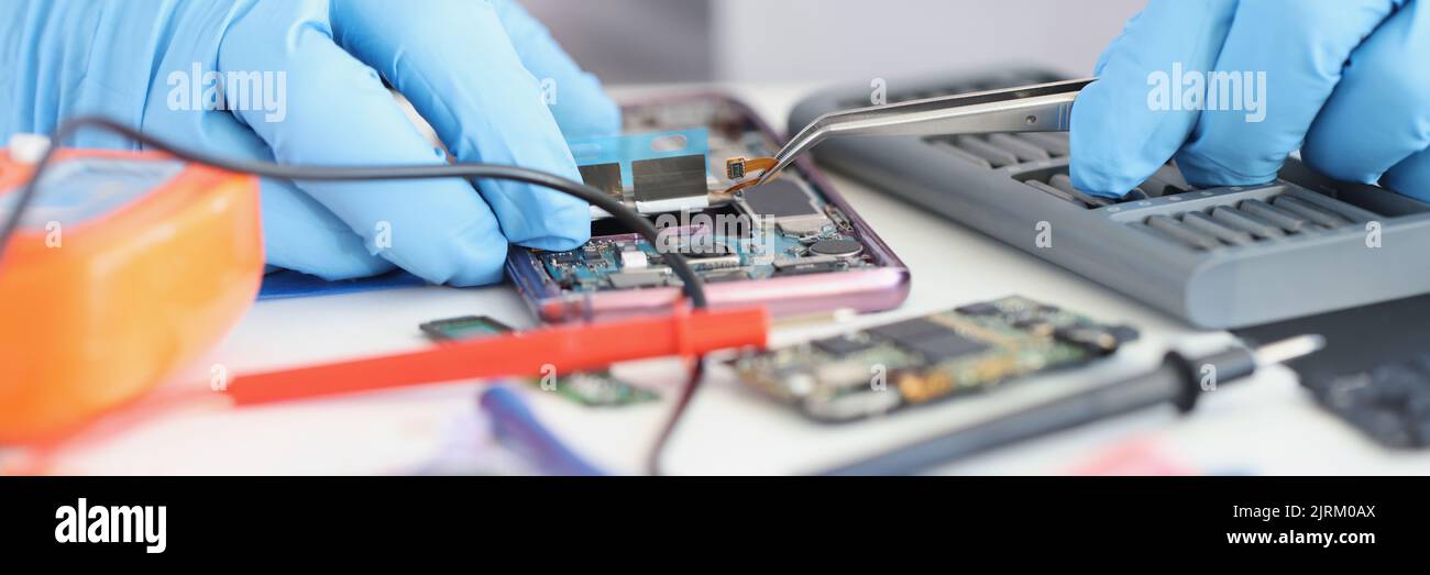 Master repairman inserting microchip into mobile phone closeup Stock Photo