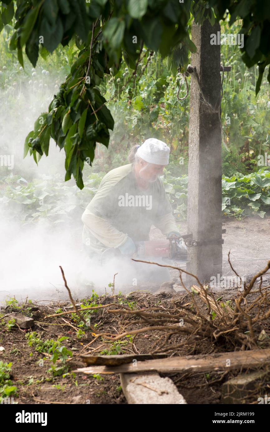 Olomouc Czech republic 9th July 2022 Man covered in dust cutting a concrete pillar using an electric diamond saw, cutter Stock Photo