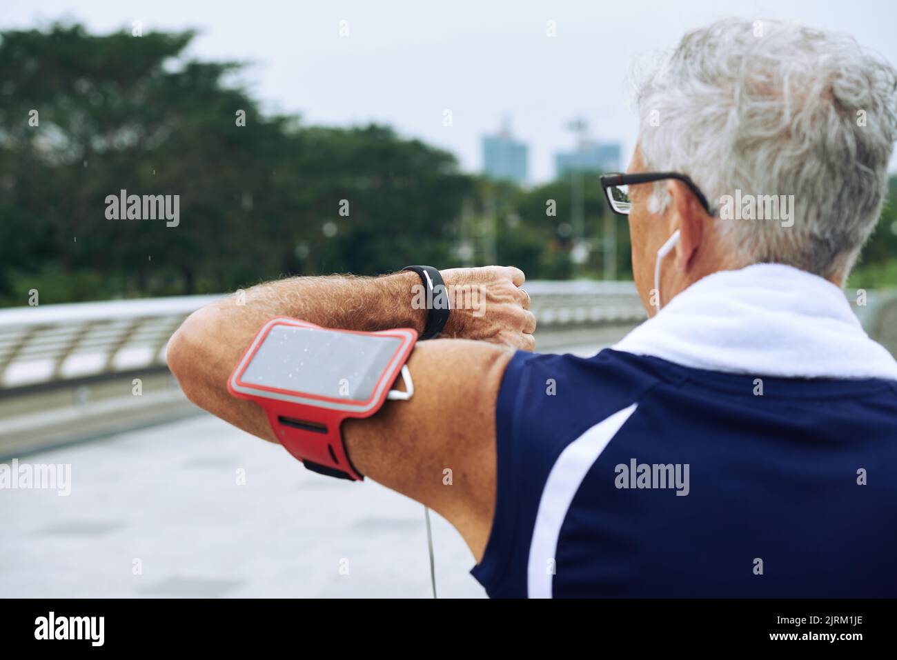 Rear view of elderly runner checking heart rate on fitness tracker when training Stock Photo