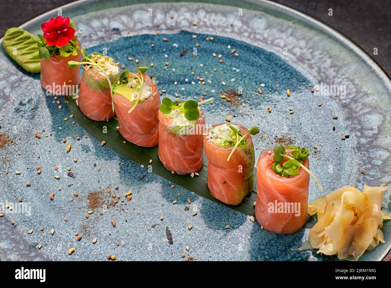 Sushi roll with salmon, cucumber and avocado, green onion, microgreens, on a plate Stock Photo