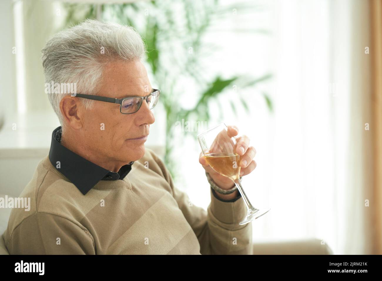 Pensive senior man with glass on white wine reading something Stock Photo