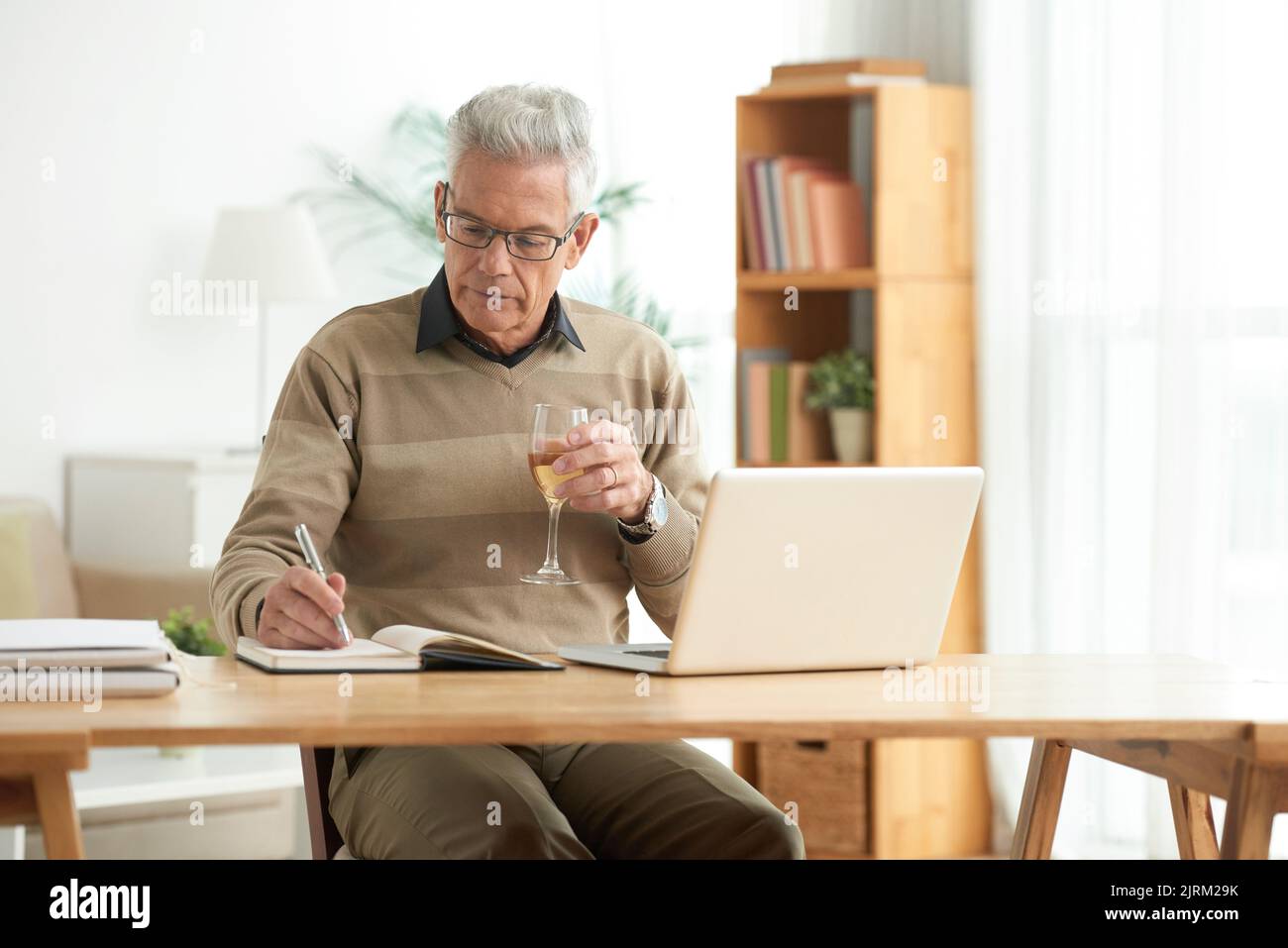 Senior man drinking wine when working at home Stock Photo
