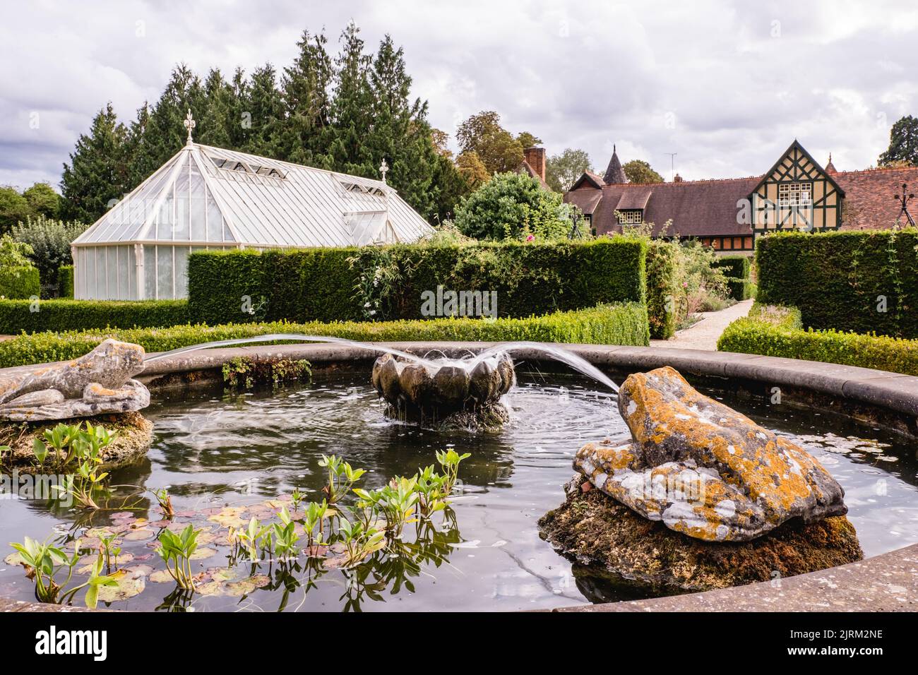 The ornamental fountain and green houses in the background at Eythrope Gardens on the Waddesdon Manor estate. Stock Photo