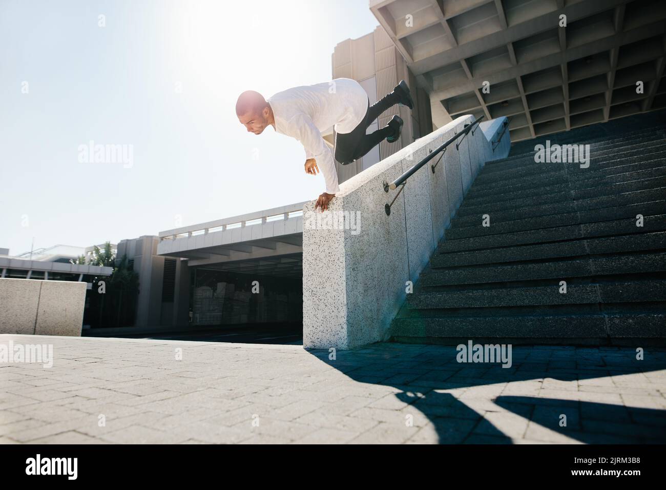 Young sportsman practicing parkour and free running outdoor by doing a wall spin. Sporty young practicing parkour in an urban space. Stock Photo