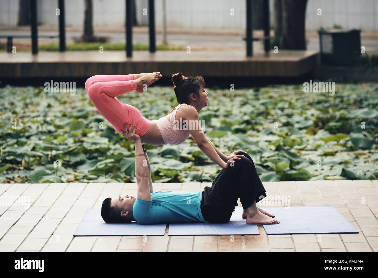 Young Vietnamese couple doing acroyoga asana outdoors Stock Photo
