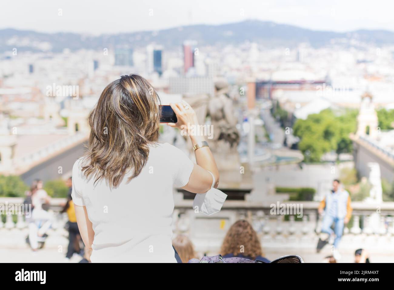 Barcelona, Spain - May 6, 2022: woman on her back taking a picture with her cell phone at the Montjuic viewpoint, Barcelona (Spain). Stock Photo
