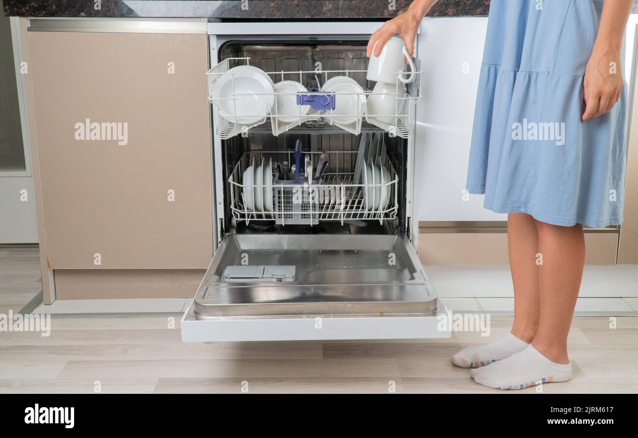 A woman listens to clean cups from the dishwasher Stock Photo