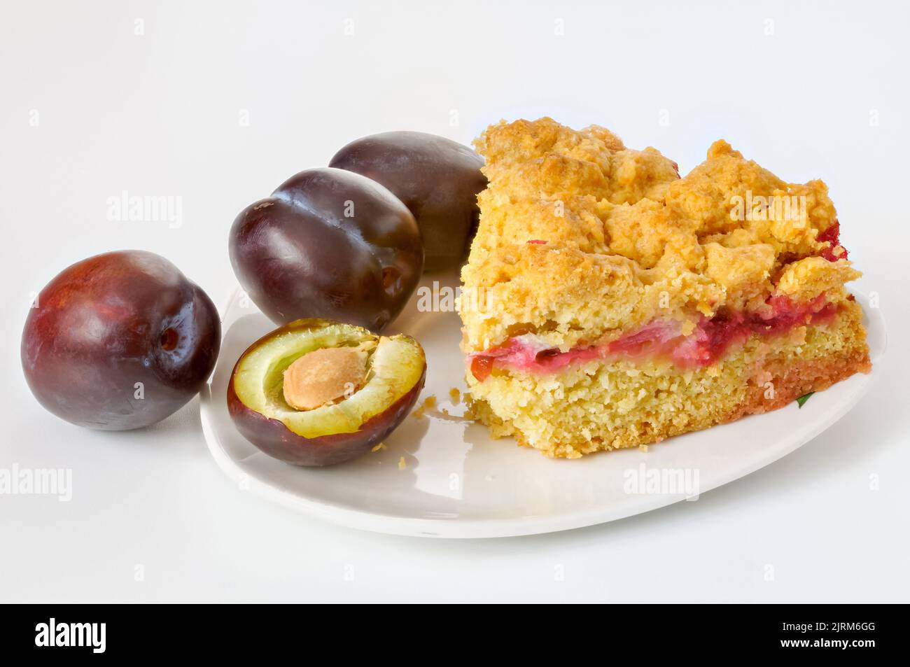 fruit cake and plums on a saucer on a white background Stock Photo