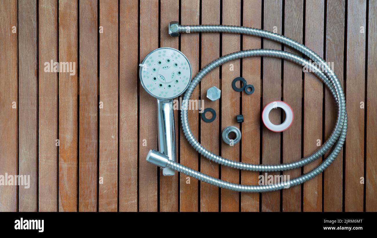 Shower head, hose, gaskets and screws for repair on a wooden background