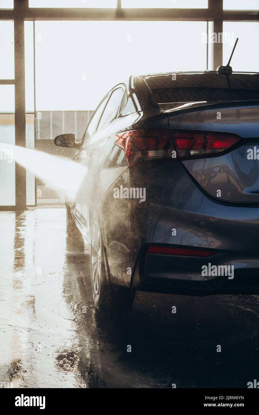 A man washes his car at a selfservice car wash using a hose with