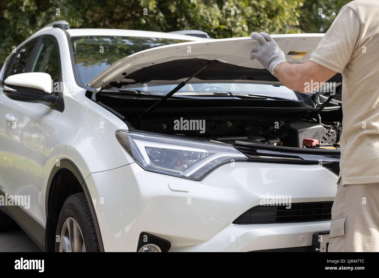man opens the hood of a white car. Hand opens the hood to access the