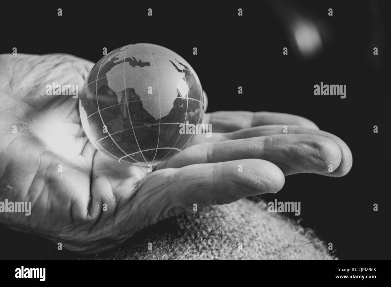 old woman holding a glass globe in her hands, black and white photo, the world is in mom's hands Stock Photo