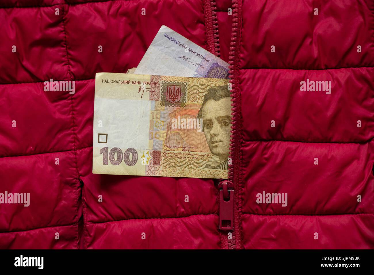 Ukrainian money one hundred and fifty hryvnia sticking out of the pocket of a red jacket, Ukrainian money, finance Stock Photo