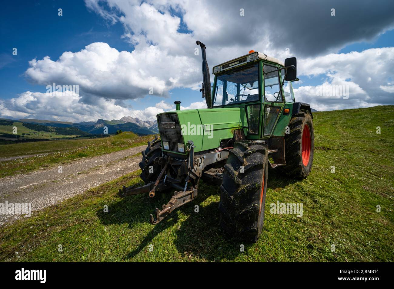 Green Tractor with red wheels in the Alps, Sud Tyrol, Summer2021 Stock Photo