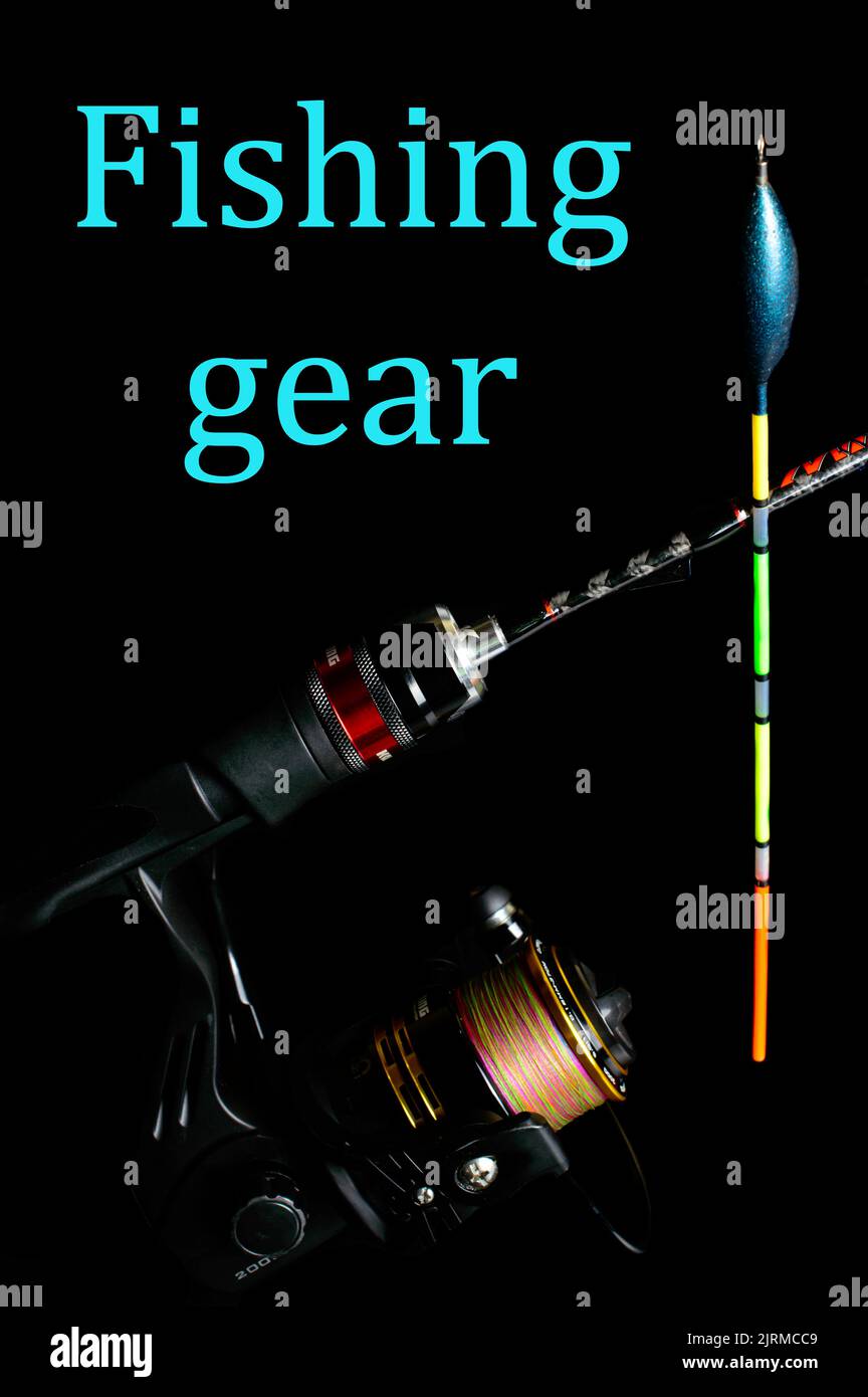Fishing rod with a reel and colorful Fishing float on a black background with inscription - fishing gear. Stock Photo