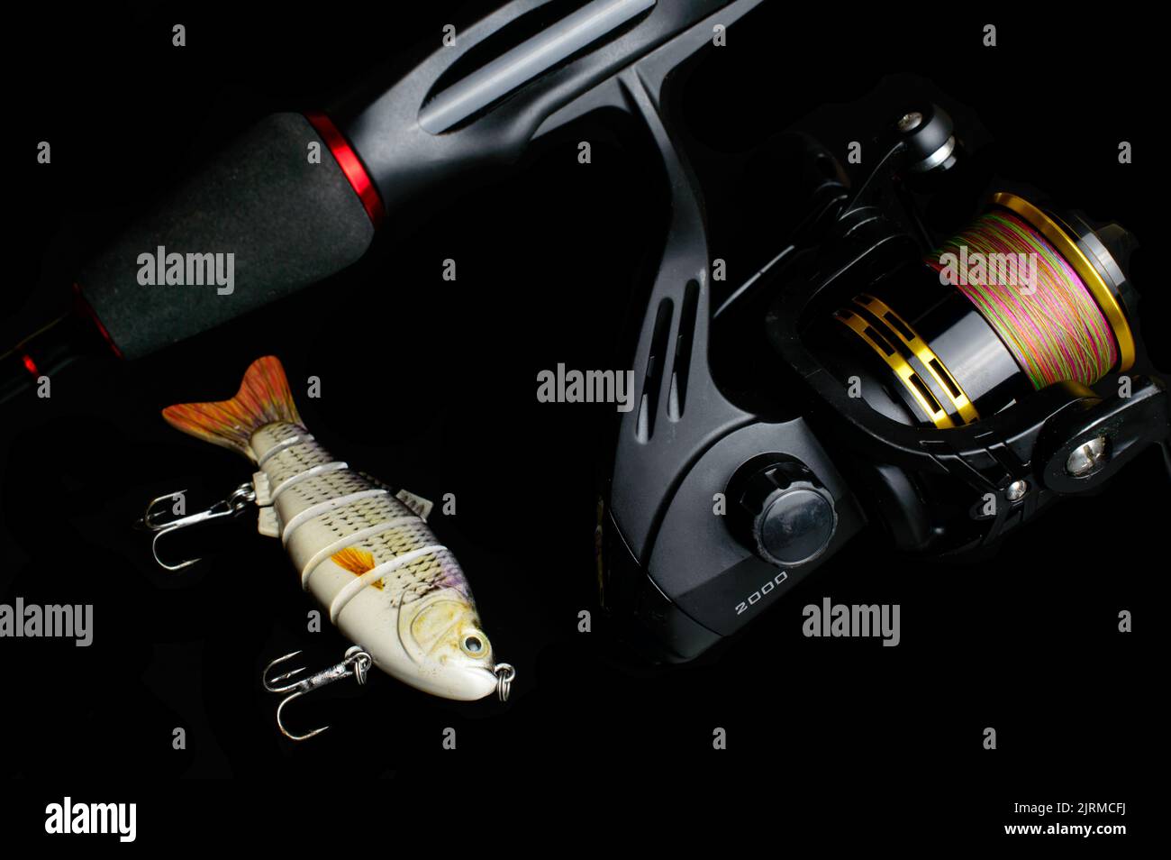 Fishing rod with reel and small lure on a black background. Stock Photo