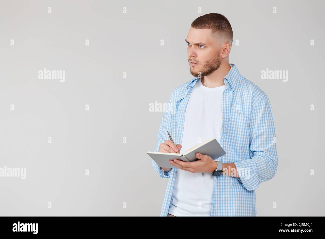 handsome man in blue shirt writing note in notebook Stock Photo