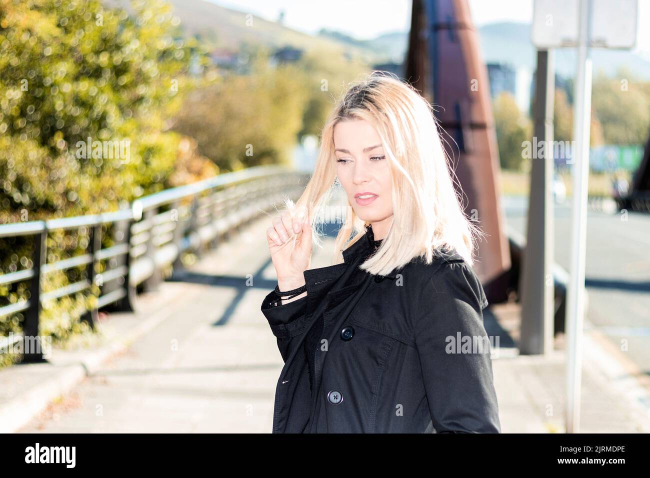 beautiful blonde woman touching her hair in a park Stock Photo