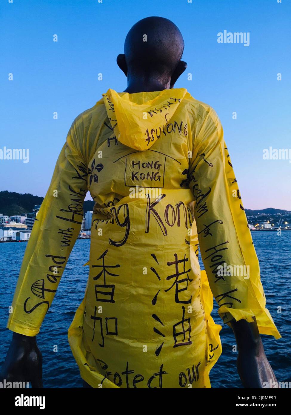 Image of 'Solace in the Wind' statue adorned with raincoat featuring messages of support for Hong Kong protests., 2019, Wellington, by Anonymous. Gift of We are Kiwi Hong Kongers, 2021. CC 0. Stock Photo
