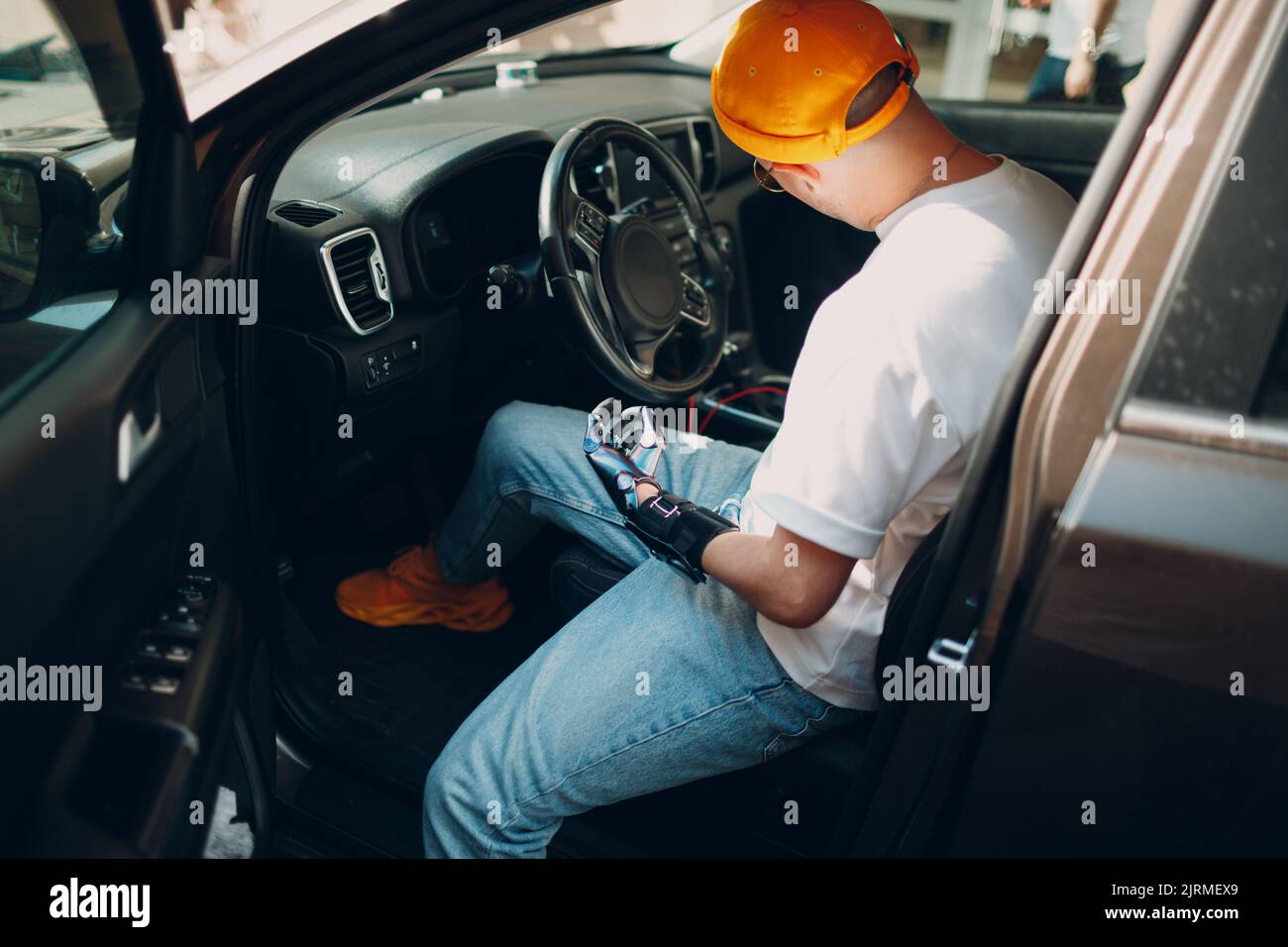 Young disabled man open vihicle car door with artificial prosthetic hand Stock Photo