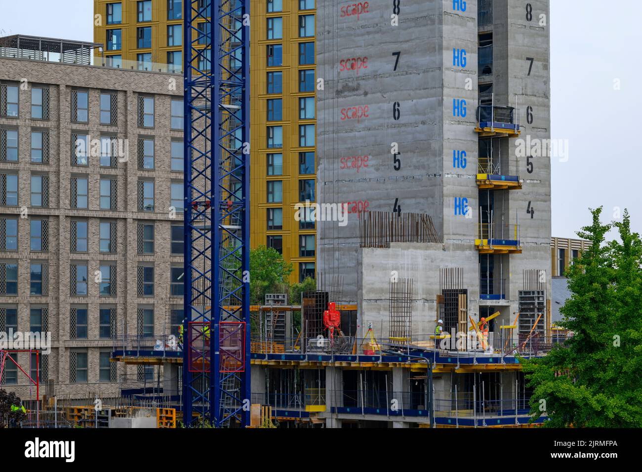 Urban tower block project (modern high-rise multi-storey apartments development, trade people work, crane mast) - Leeds, West Yorkshire, England, UK. Stock Photo