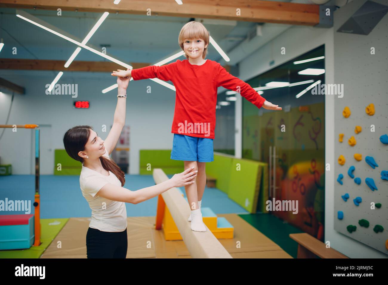 Kids doing balance beam gymnastics exercises in gym at kindergarten or