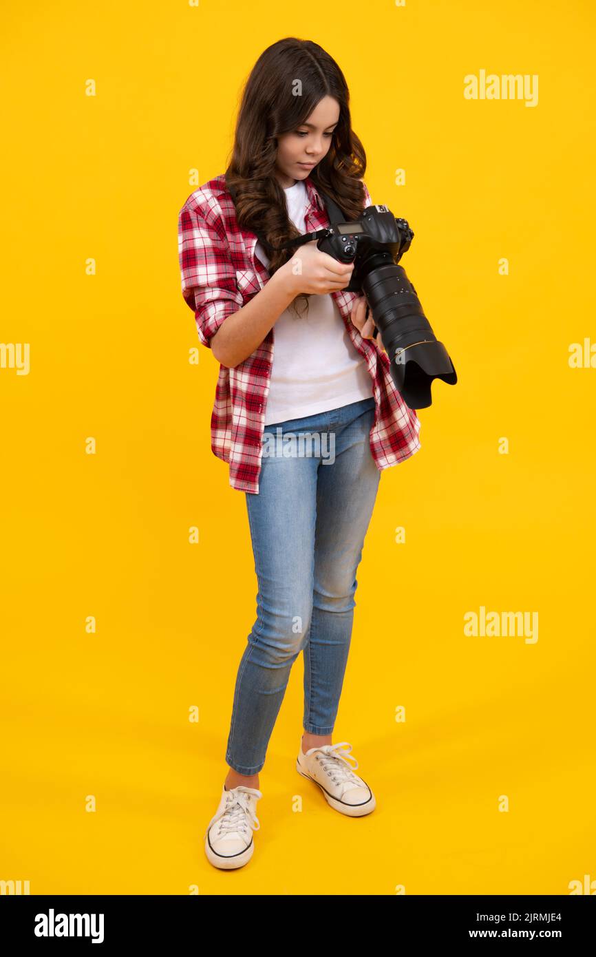 Teenager lifestyle, teen hipster hold professional camera. Girl with photo camera photographing, isolated on studio background. Stock Photo