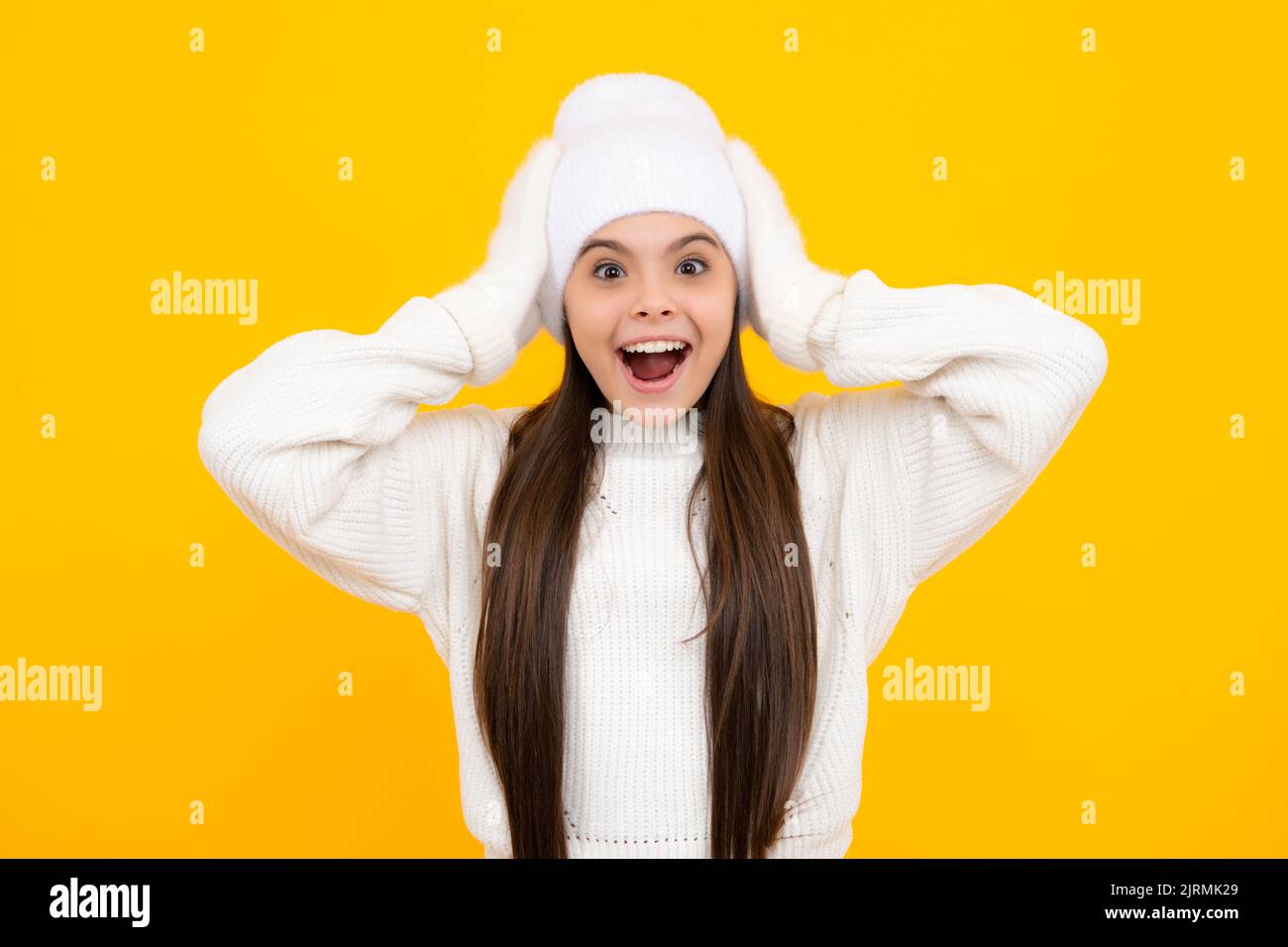 Child with positive expression, joyful and exciting, dressed in casual winter cloth over yellow background with empty space. Excited face. Amazed Stock Photo