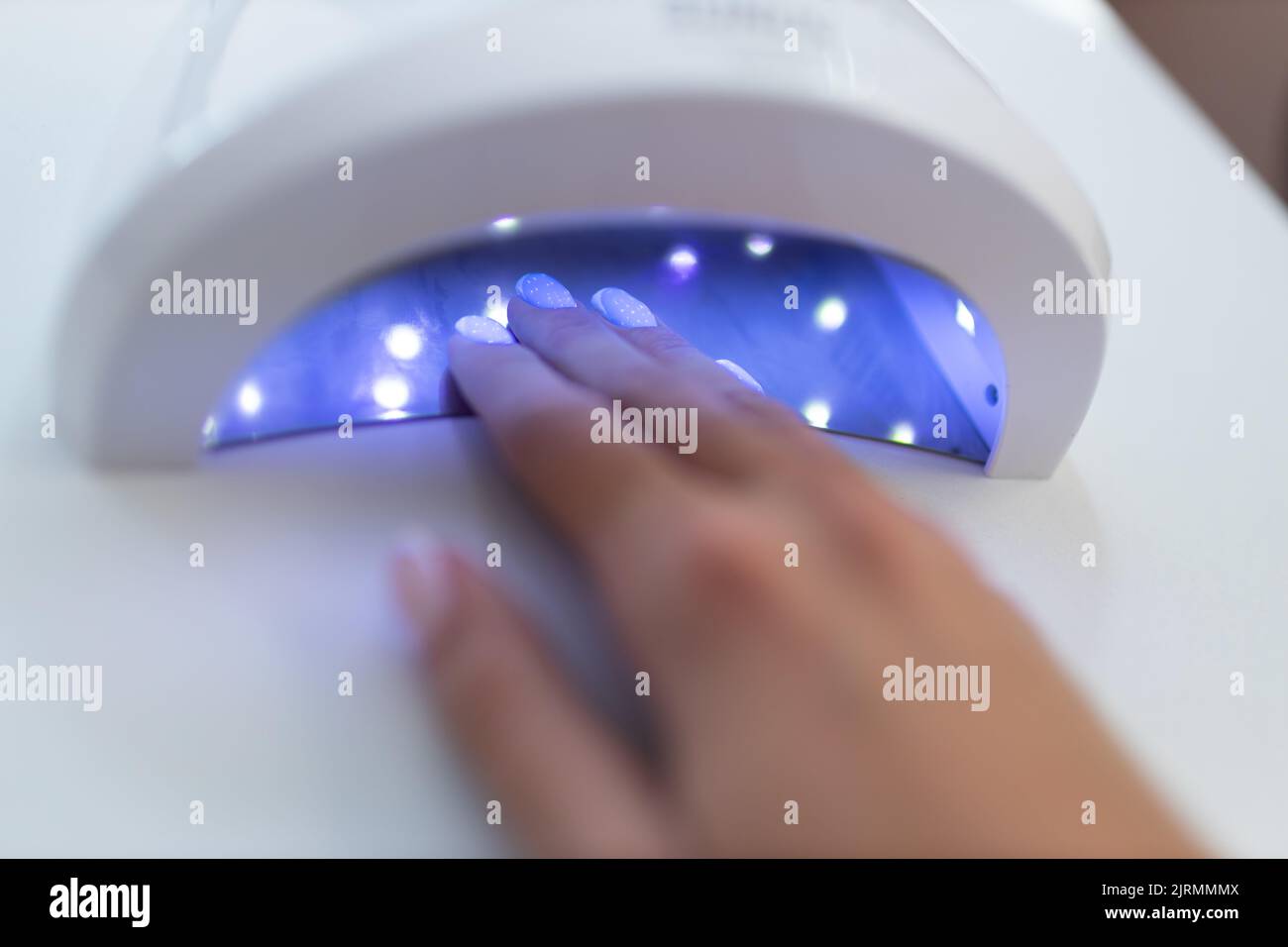 Female hand inside drying UV light machine in nail salon Stock Photo