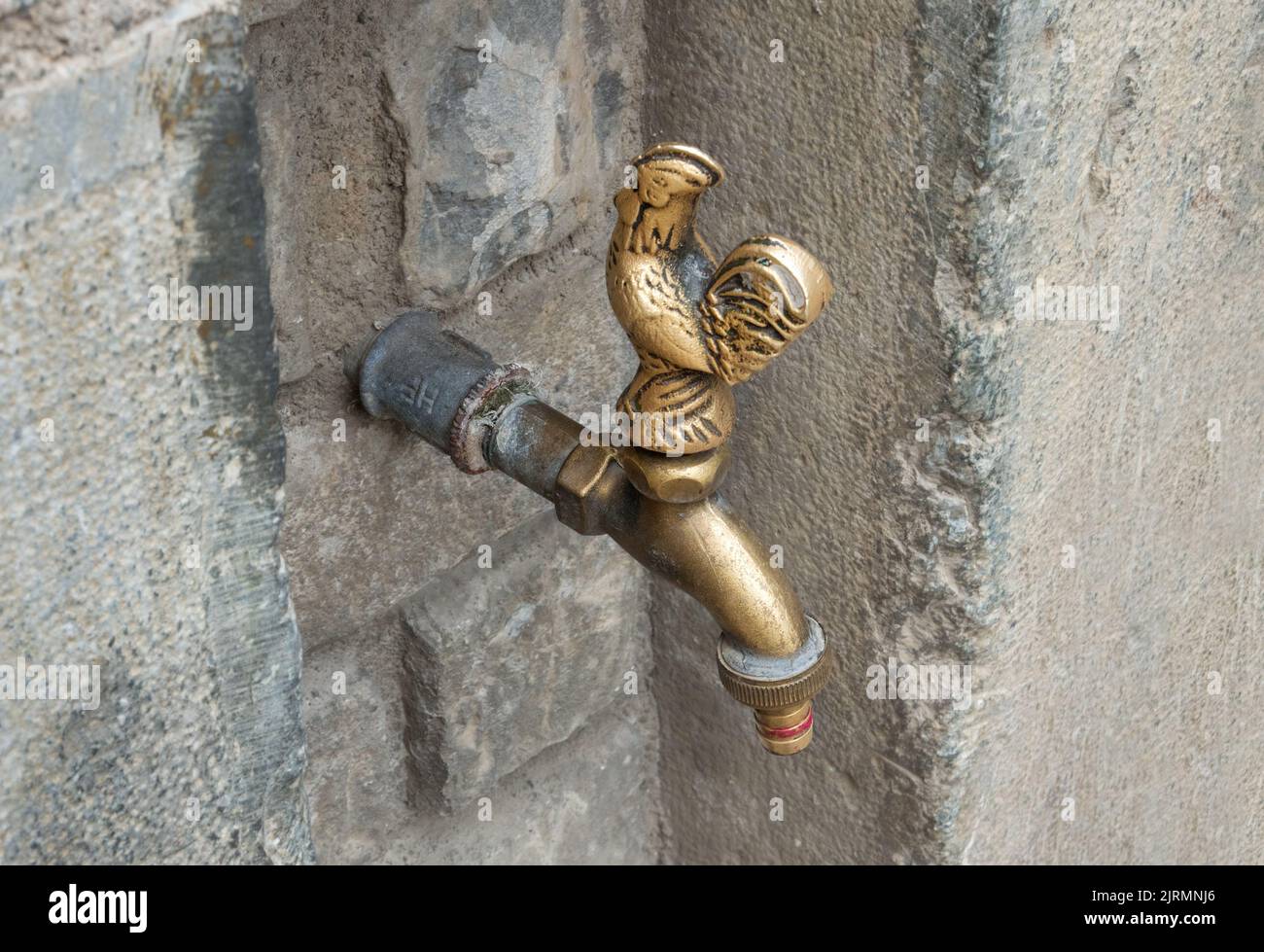 Antique brass water tap with handle in the shape of a rooster. Stock Photo
