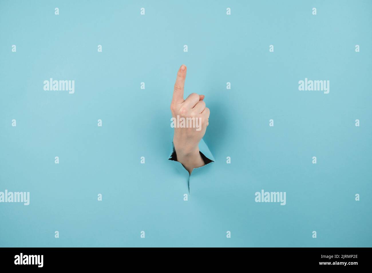 A woman's hand sticking out of a hole from a blue background shows her ...