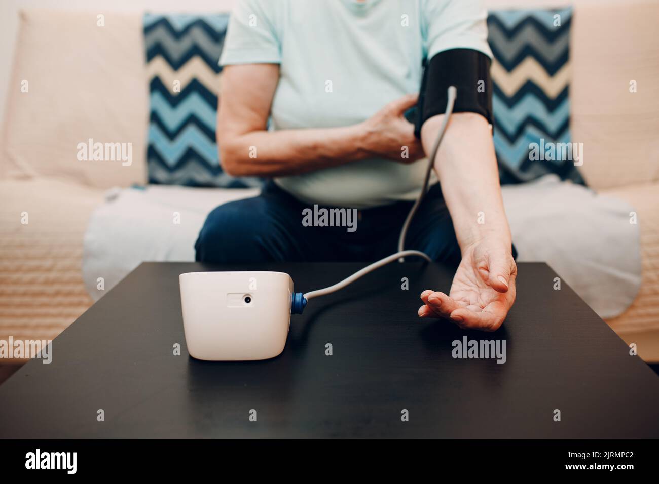 Senior woman taking measures blood pressure at home indoor. Self care