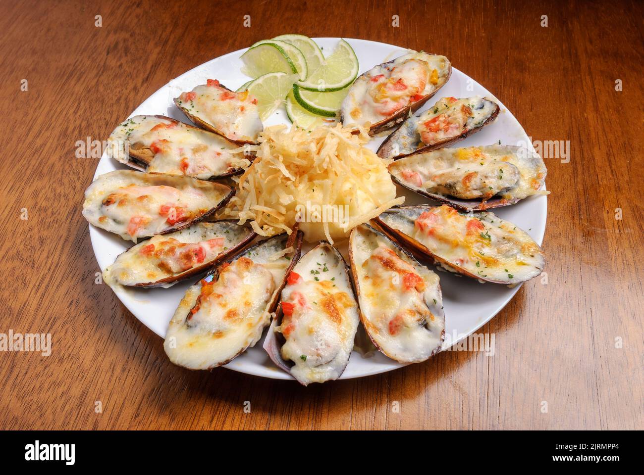 Baked mussels au gratin with mashed potatoes on a white plate on wooden