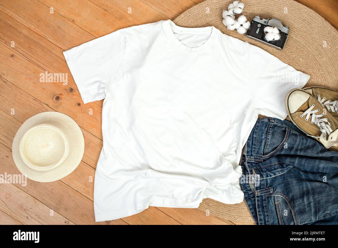 Unisex white shirt , flat lay on wooden boards with blue jeans, sneakers and cotton flowers, Creative mockup for design presentation. Stock Photo